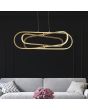 Searchlight Clip 61775GO sfeerfoto van goudkleurige hanglamp van 74,5cm met ronde plafondplaat en drie ovale ringen in drie afmetingen die in elkaar kunnen draaien met LED strip aan de buitenzijde in een woonkamer boven een grijze bank voor een zwarte muu