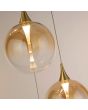LED unit in het glas van de hanglamp met zwarte plafondplaat van 35cm met vijf pendels met elk een kap met goudkleurige bovenzijde en een obre amber kleurige glazen bol met geïntegreerde LED