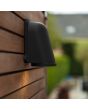 Sfeerfoto van Lutec Ancor zwarte wandlamp van 14,6 cm hoog voor buiten met een naar beneden gericht spot langs een houten muur