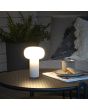 Sfeerfoto van Konstsmide Antibes wit aluminium tafellamp voor buiten met wit glazen kap van 25 cm hoog. op een tuintafel