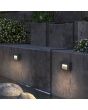 Sfeerfoto van twee Lutec Arteo antraciet grijze rechthoekige wandlampen van 23 cm breed met lichtvenster naar voren en beneden boven een vijver