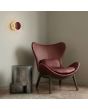 sfeerfoto van bruine ronde wandlamp van 28 cm in diameter met brede plexiglas rand en geïntegreerde LED voor licht langs de muur aan de muur naast een kuipstoel