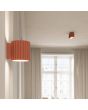 Sfeerfoto van Sollux Aura perzikkleurig geribbeld cilindervormige wandlamp van 10 cm in hoogte met een G9 lampje erin met een plafondlamp uit dezelfde serie op de achtergrond