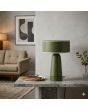 Sfeerfoto van olijfgroene kunststof tafellamp van 28 cm hoog met een omhoog draaiend deel van de kap voor verschillende lichtscenes op een stenen tafel voor een muur