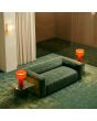 sfeerfoto van twee rode kunststof tafellampen van 28 cm hoog met een omhoog draaiend deel van de kap voor verschillende lichtscenes naast een groene bank