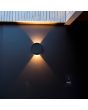 Sfeerfoto met lichtbeeld van de Lutec Belka antraciet grijze platte wandlamp van 19 cm in diameter en slechts 6,3 cm diep met zonnepaneel op de voorzijde