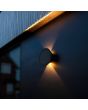 Sfeerfoto van zijaanzicht met lichtbeeld van de Lutec Belka antraciet grijze platte wandlamp van 19 cm in diameter en slechts 6,3 cm diep met zonnepaneel op de voorzijde