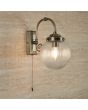 Searchlight Belvue 3259AB sfeerfoto van klassiek bronzen badkamer wandlamp met trekschakelaar en bolvormig geribbeld glazen kap een een bruin stenen badkamer muur