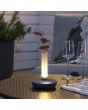 Sfeerfoto van Konstsmide Biarritz vaasje van 20,5 cm hoog met antraciet grijze voet en mat glazen buisje met LED onderin op een tuintafel