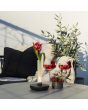 Sfeerfoto van Konstsmide Biarritz vaasje van 20,5 cm hoog met zwarte voet en mat glazen buisje met LED onderin op een tuintafel met twee aardbeien cocktails