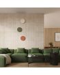 Sfeerfoto van beige, olijfgroen en okerrood ronde wandlamp Borgen van 30 cm in diameter voor indirect licht langs de muur boven een groen bankstel