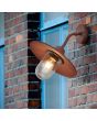 Trio Brenta 201760124 sfeerfoto van roestbruine wandlamp voor buiten met een transparant glas over de lichtbron aan een ruw stenen buitenmuur