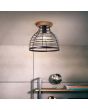 Brilliant Avia 99563/76 sfeerfoto van industriele plafondlamp met ronde houten plafondplaat en kap van zwart metaaldraad boven een stellingkast