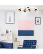 Brilliant Grove 99302/86 sfeerfoto van zwarte spot met twee stangen met elk twee spotjes met dubbele kap van zwart textiel en daarbinnen goudkleurig metaalgaas in een woonkamer met blauwe stoel en bank