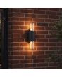 zwarte up en down wandlamp voor buiten van kunststof met amber kunststof kappen en een hoogte van 30 cm naast een voordeur