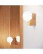 Sfeerfoto van Sollux Bulbo rechthoekige houten wandlamp met wit bolvormig glazen kap van 12 cm in diameter naast een spiegel