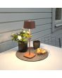Sfeerfoto van Konstsmide Capri terracotta kleurige tafellamp op batterijen van 37 cm hoog en touch dimmer op de kop op een tuintafel naast een vaas en een ontbijtje