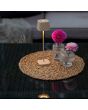 Sfeerfoto van Konstsmide Capri zandkleurige oplaadbare aluminium tafellamp voor buiten van 25 cm hoog met een vierkant kapje met touch dimmer op een rieten tuintafel naast twee vaasjes met een bloem