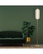 Searchlight Capsule EU28806SB sfeerfoto van messing kleurige vloerlamp met cilindervormige kap van geribbeld acryl naast een groene bank en groene plant in een goudkleurige pot