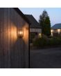 Sfeerfoto van Konstsmide Carpi zwarte rechthoekige wandlamp voor buiten van 36,5 cm hoog met mat ribbelglazen ruitjes tegen een houten wand van een woning