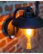 Sfeerfoto van bovenaanzicht Lutec Cate antiek bruin zwarte wandlamp voor buiten van 22cm hoog met hangende lantaarn van transparant kegelvormig glas