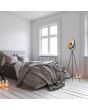 Sfeerfoto van Reality Chewy zwarte tripod van 160 cm hoog met richtbare schaalvormige kap van 40 cm met goudkleurige binnenzijde en zwart metalen afscherming voor de lichtbron voor indict licht via de kap in een slaapkamer naaste een tweepersoonsbed