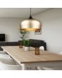Trio Chiron 310890108 sfeerfoto van mat messing bolvormige hanglamp met mat zwarte bovenzijde boven een eettafel in een moderne woonkamer