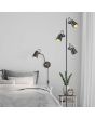 Trio Edward 208870132 sfeerfoto van zwart met goudkleurige wandspot met scharnierende arm en snoer met stekker naast een bed met een vloerlamp uit dezelfde serie ernaast