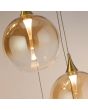 glas van de hanglamp met zwarte plafondplaat van 45cm met acht pendels met elk een kap met goudkleurige bovenzijde en een obre amber kleurige glazen bol met geïntegreerde LED