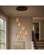 hanglamp met zwarte plafondplaat van 45cm met acht pendels met elk een kap met goudkleurige bovenzijde en een obre amber kleurige glazen bol met geïntegreerde LED boven een trapgat