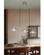 Sfeerfoto van Reality Eluna oud brons kleurige hanglamp van 100 cm lang met drie schijfvormige kappen van geribbeld helder glas met een diameter van 25 cm boven een houten eettafel