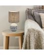 Trio Esna R50661025 sfeerfoto van tafellamp met beige voet met de tekst "love" en een bruine kap van textiel op een houten bijzettafeltje naast een grijze bank met beige kleedje