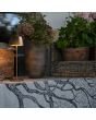 Sfeerfoto van Konstsmide Eze mat koper kleurige draadloze tafellamp voor buiten van 32 cm hoog naast een houten krat en plantenpotten