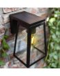 Sfeerfoto van bovenaanzicht Lutec Fia zwarte wandlamp voor buiten van 20,7 cm hoog met zonnepaneel bovenop en E27 peertje