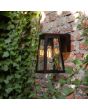 Sfeerfoto van zijaanzicht Lutec Fia zwarte wandlamp voor buiten van 20,7 cm hoog met zonnepaneel bovenop en E27 peertje
