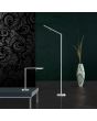 Trio Filigran 420490107 sfeerfoto van staal kleurige buisvormige vloerlamp met langwerpig glazen plaatje
