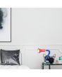 Trio Flexo 5028010-17 sfeerfoto van kleurrijke klemspot met flexibele blauwe arm, groene klem, rode kap en gele details geklemd aan een nachtkastje naast een bed