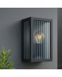sfeerfoto van zwart rechthoekige wandlamp Getta voor buiten van 26 cm hoog met geribbeld glazen ruitjes tegen een grijze buitenmuur