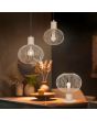 Trio Gila 565790166 sfeerfoto van zand kleurige 37cm hoge tafellamp met bolvormige kap van metaaldraad op een kastje met twee hanglampen uit dezelfde serie