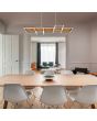 Trio Harper 322910532 sfeerfoto van hanglamp met zwarte plafondbalk en houten plank met zwarte vierkanten ramen eronder met geïntegreerde LED strips boven een eettafel in een moderne woonkamer