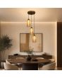 hanglamp met brons kleurige plafondplaat met een diameter van 25 cm en drie pendels met een kap van mat met helder gestreept amber kleurig glas met een diameter van 11cm boven een ronde eettafel