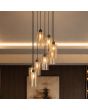 hanglamp met brons kleurige plafondplaat met een diameter van 40 cm en acht pendels met een kap van mat met helder gestreept amber kleurig glas met een diameter van 11cm