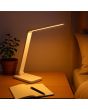Sfeerfoto van de Brilliant Lomina oplaadbare witte bureaulamp van 38 cm hoog met twee scharnierpunten en langwerpige LED unit in de kop op een houten nachtkastje