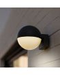 Sfeerfoto van Lutec Looma antraciet grijze wandlamp voor buiten met een bolvormige kap van 10 cm in diameter met wit kunststof onderzijde aan een wit stenen muur
