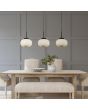 Searchlight Lumina 10271-3BK sfeerfoto van zwarte hanglamp met drie pendels met elk een kap van opaal geribbeld glas boven een houten eettafel met schaal en plant