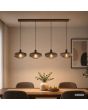 koffiebruine hanglamp met een langwerpige plafondplaat van 110 cm en vier pendels met elk een geribbeld glazen kap met een diameter van 28 cm boven een eettafel in een eetkamer