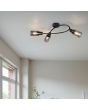 Sfeerfoto van Reality Mars zwarte plafondspot van 45 cm lang met gebogen stang met drie spotjes met elk een rookglazen kapje met een diameter van 8 cm in een woonkamer voor een raam