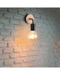 Sfeerfoto van Casalum Merida zwarte wandlamp van 15,5 cm hoog met houten plaatje over het wandplaatje en vrij hangende globelamp aan een ruwstenen witte muur