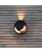 Sfeerfoto van Lutec Moov antraciet grijs schijfvormige wandlamp voor buiten met een diameter van 21,1 cm met lichtbundel naar boven en twee draaibare schijven met richtbare LED bundels