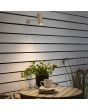 Sfeerfoto van Konstsmide Multi zandkleurige spot met wandhouder waarvan de spot oplaadbaar is met de USB kabel boven een tuintafel met plantenpot
